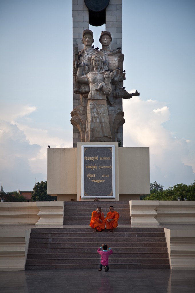 Monks ask a passing boy to take their photo in front of the Vietnamese Friendship Monument